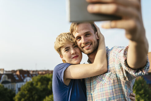 Junges Paar, das sich umarmt und ein Selfie mit einem Smartphone macht - FOLF02895