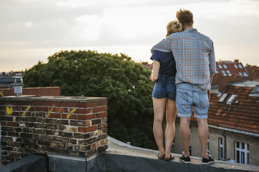 Junges Paar steht auf einem Dach und betrachtet die Aussicht - FOLF02897