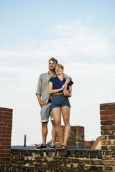 Lächelndes junges Paar auf dem Dach stehend - FOLF02898
