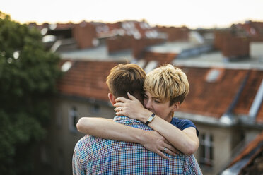 Young couple hugging on rooftop at sunset - FOLF02903