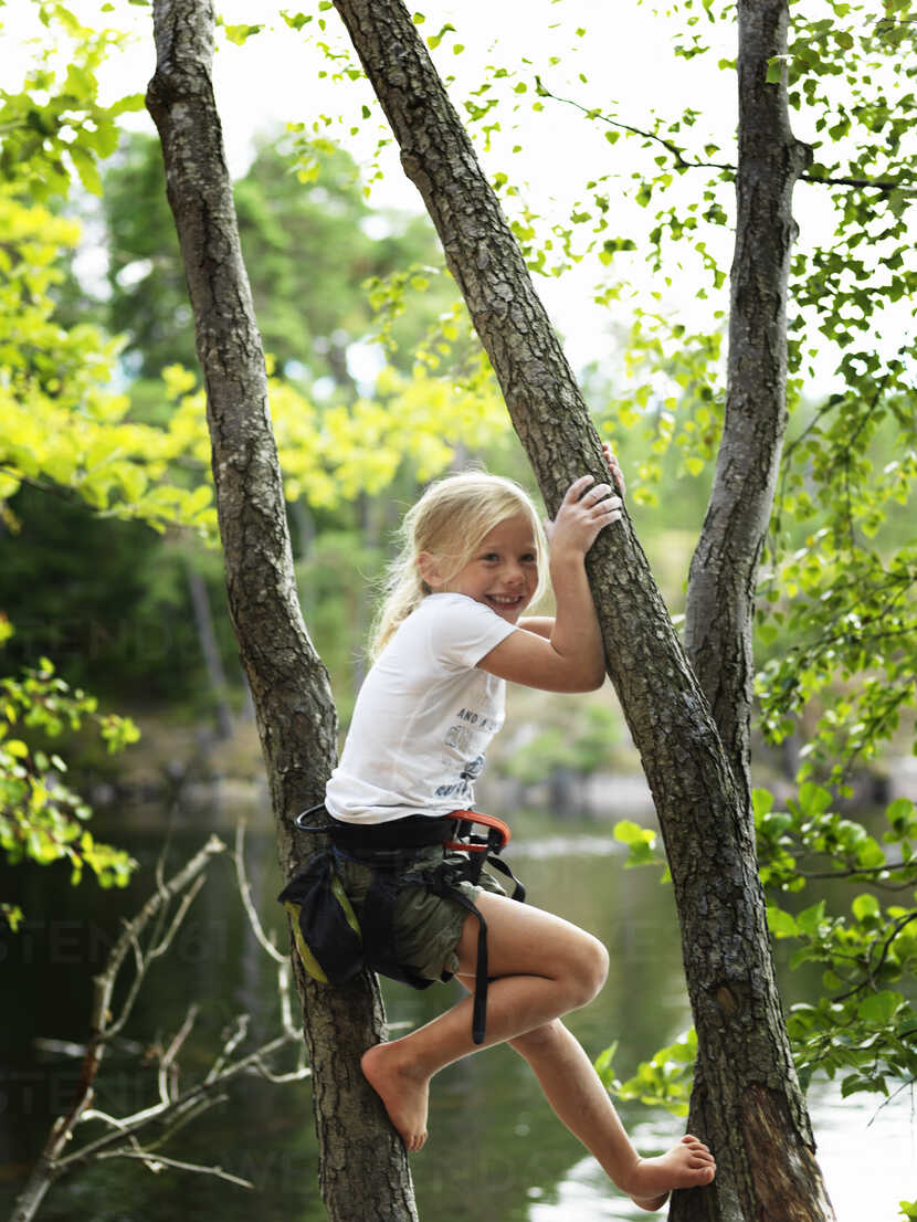 Smiling girl climbing tree stock photo