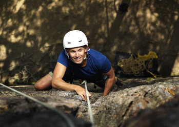 Lächelnder Mann klettert auf Felsen - FOLF02913