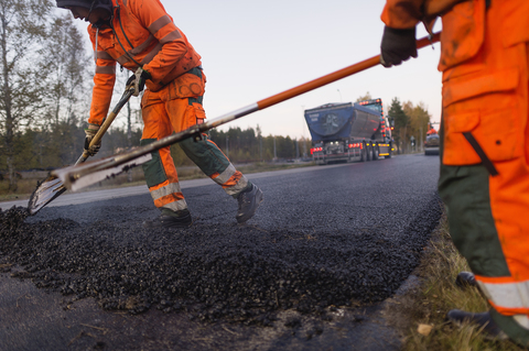 Three manual workers repairing road stock photo