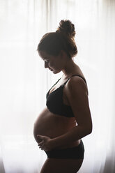 Happy pregnant woman in bra and panties holding stomach stock photo