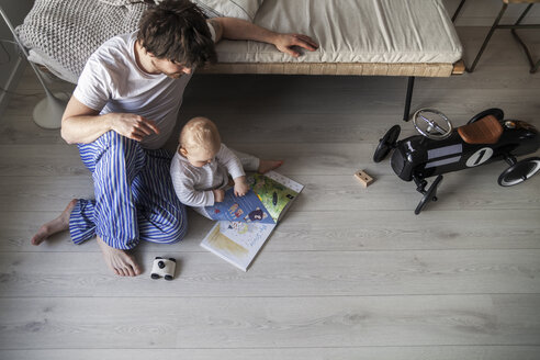 Vater und kleiner Sohn sitzen auf dem Boden im Wohnzimmer - FOLF03293