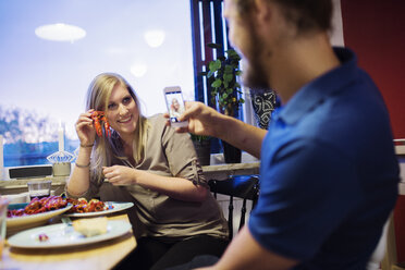 Man photographing woman holding crayfish - FOLF03301