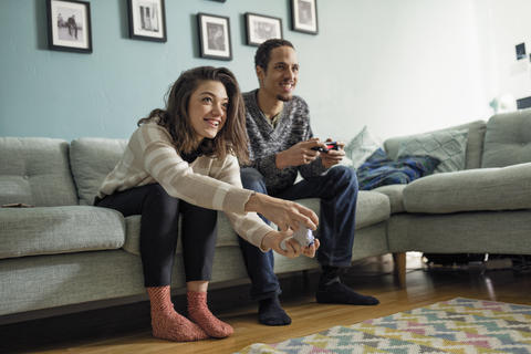 Junges Paar spielt Videospiele im Wohnzimmer, lizenzfreies Stockfoto
