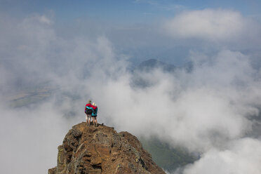 Hohe Winkel Ansicht der Wanderer mit Arme um die Schultern stehen auf Cheam Peak gegen Himmel inmitten von Wolken - CAVF30913