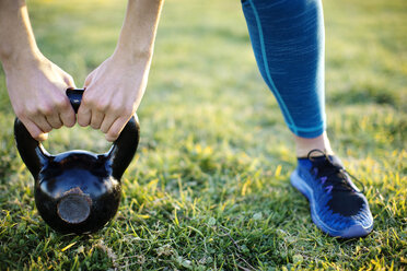 Cropped image of athlete exercising with kettlebell on field - CAVF30985