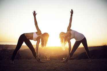 Freundinnen trainieren auf einem Berg gegen den klaren Himmel bei Sonnenaufgang - CAVF31047