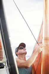 Mann mit Sonnenbrille macht Segelboot gegen klaren Himmel - CAVF31052