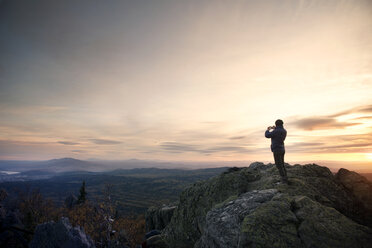 Frau bei Sonnenuntergang auf einem Berg stehend - CAVF31084