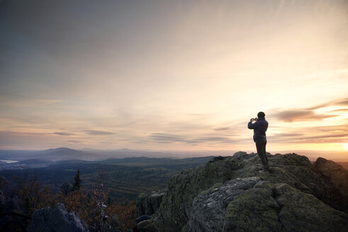 Frau bei Sonnenuntergang auf einem Berg stehend - CAVF31084