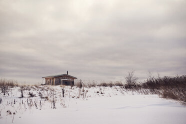 Haus auf schneebedecktem Feld gegen bewölkten Himmel - CAVF31093