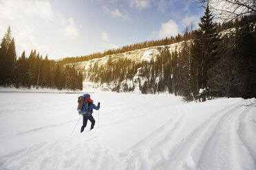 Rear view of hiker walking on snowcapped landscape - CAVF31107