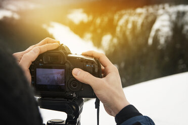 Ausgeschnittenes Bild eines Mannes, der mit einer Digitalkamera auf einem schneebedeckten Berg fotografiert - CAVF31108