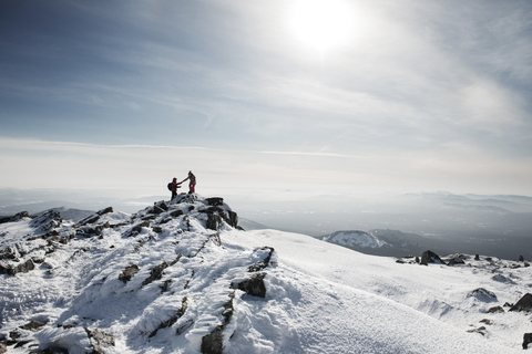 Freunde wandern auf schneebedecktem Berg gegen den Himmel, lizenzfreies Stockfoto