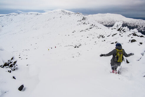 Rückansicht eines Wanderers, der auf einem schneebedeckten Berg gegen den Himmel hinunterläuft - CAVF31160