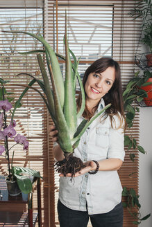 Porträt einer lächelnden Frau, die eine Aloe vera hält - SKCF00358