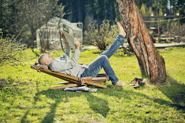 Mid adult man reading newspaper on sunlounger - FOLF03612