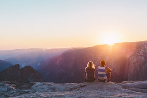 Mann und Frau beobachten den Sonnenuntergang in den Bergen im Yosemite National Park - FOLF03637