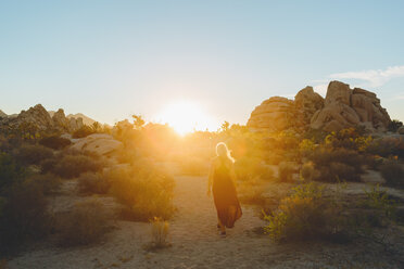 Woman wearing dress hiking in Joshua Tree National Park at sunset - FOLF03641