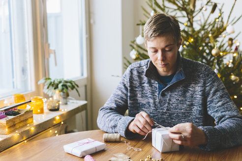 Mann wickelt Weihnachtsgeschenke ein - FOLF03643