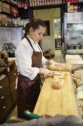 Frau schneidet Brot im Laden - FOLF03718