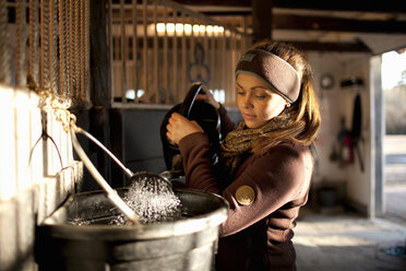Frau gießt Wasser von der Gießkanne in den Eimer - FOLF03809