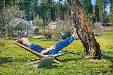Mid adult woman lying down on sunlounger in garden - FOLF03844