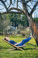 Mid adult woman lying down on sunlounger in garden - FOLF03845