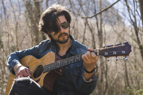 Junger Mann spielt Gitarre im Freien, lizenzfreies Stockfoto