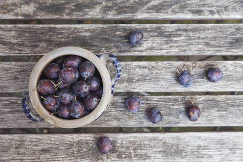 Frische Pflaume in Steinguttopf auf Gartentisch, lizenzfreies Stockfoto