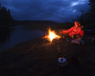 Mann am Lagerfeuer am Flussufer - FOLF03887