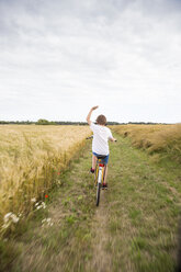 Junge fährt Fahrrad in einem Weizenfeld - FOLF03912