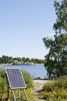 Solarmodul auf Gras und eine Bucht mit Wasser im Hintergrund - FOLF03934