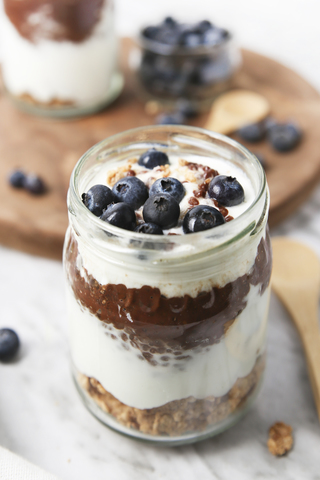 Ein Glas Chia-Pudding-Parfait mit Schokolade und Joghurt mit Blaubeeren und Granola, lizenzfreies Stockfoto