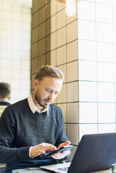 Businessman using smart phone in cafe - FOLF04086