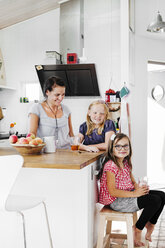 Mother and daughters smiling in kitchen - FOLF04104