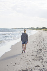 Rückansicht einer reifen Frau, die am Strand spazieren geht - FOLF04211