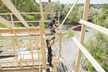 Mittlere erwachsene Männer beim Bau eines Holzhauses - FOLF04276