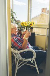 Älterer Mann liest ein Buch auf einer Loggia - FOLF04278