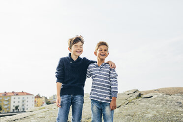 Boys standing on asphalt mound and laughing - FOLF04285