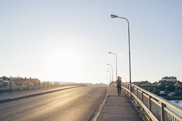 Junge Frau joggt auf einer Brücke - FOLF04288