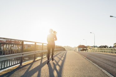 Junge Frau joggt auf einer Brücke - FOLF04289