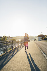 Junge Frau joggt auf einer Brücke - FOLF04291