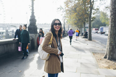 Smiling woman standing on pavement at Victoria Embankment in London - FOLF04302