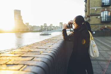 Mid adult woman taking pictures at riverbank in Rotherhithe - FOLF04307