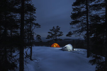 Beleuchtete Zelte auf dem Gipfel eines Berges im Winterwald - FOLF04337