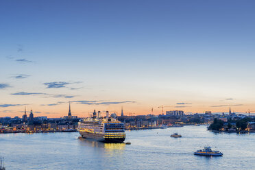 Illuminated city waterfront in Stockholm at sunset with ferry and ships passing by - FOLF04391